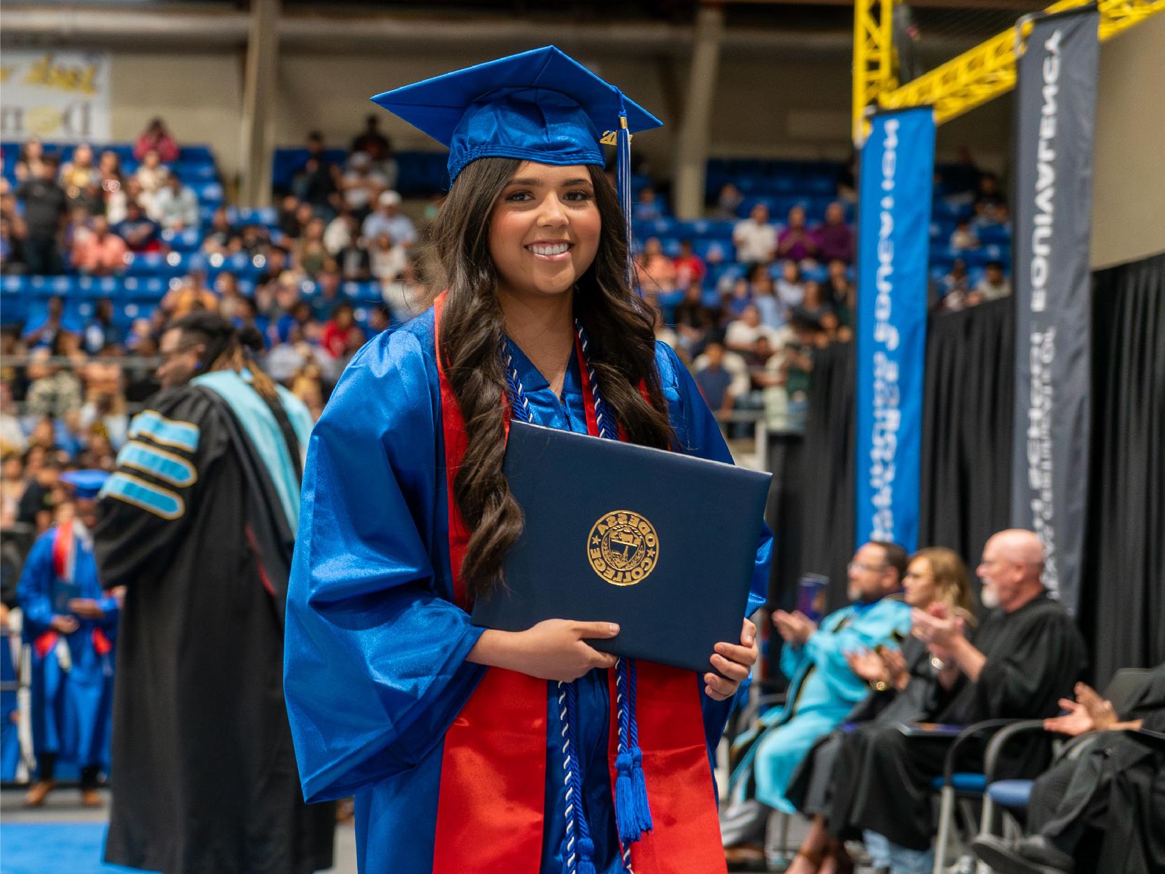 Brunette Female in Blue Cap and Gown Holding Diploma